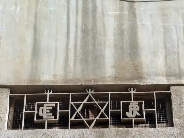 fachada de una pequeña reja de ventilación con la estrella judía y dos logotipos de Cartonera Española
