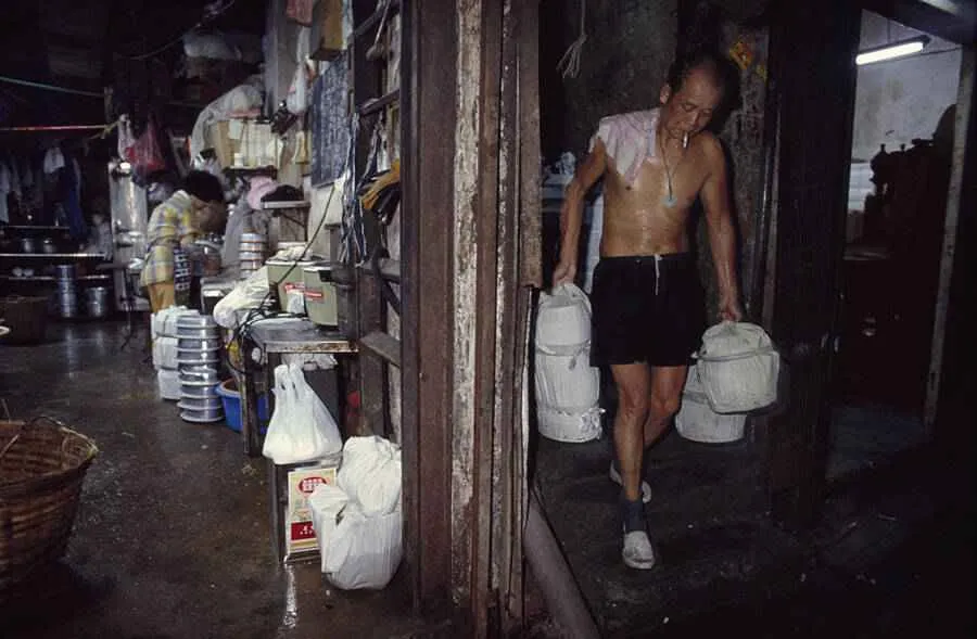 Un hombre lleva loncheras para entregarlas en oficinas y talleres en la ciudad amurallada de Kowloon