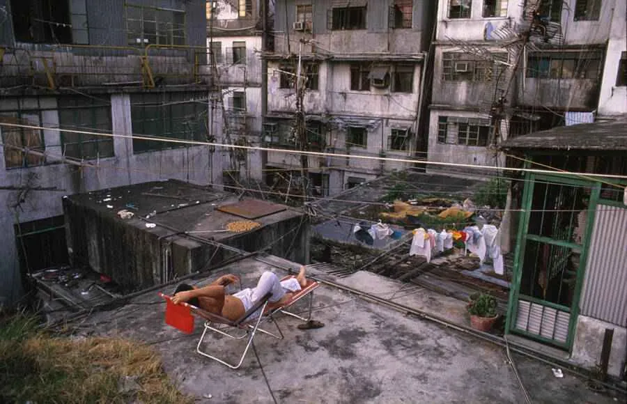 Un hombre yace sobre un tejado en la ciudad amurallada de Kowloon