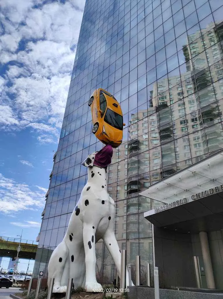 un perro dalmata gigante balanceando un taxi amarillo en su nariz