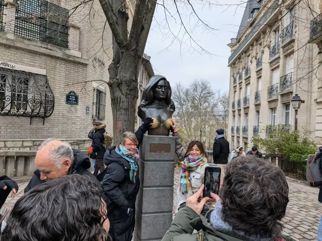 varios turistas frotando el busto de dalida en sus senos