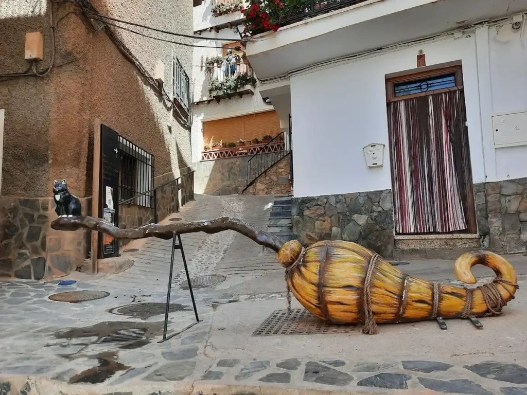 escultura de una escoba de brujas con un gato negro