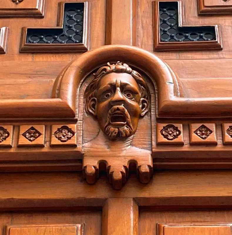 Rostros expresivos grabados en la antigua puerta del Divino Salvador