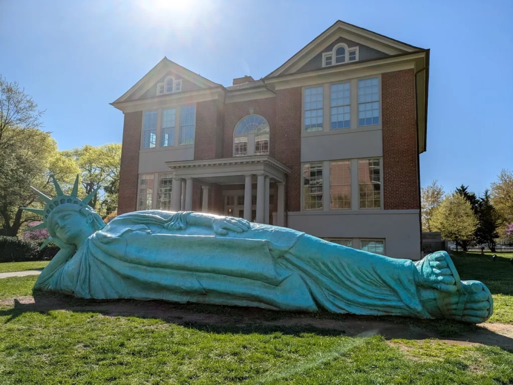 escultura de la estatua de la libertad tumbada sobre el cesped