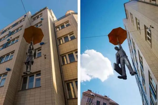 estatuas de un hombre y mujer aterrizando en praga con ayuda de un paragua