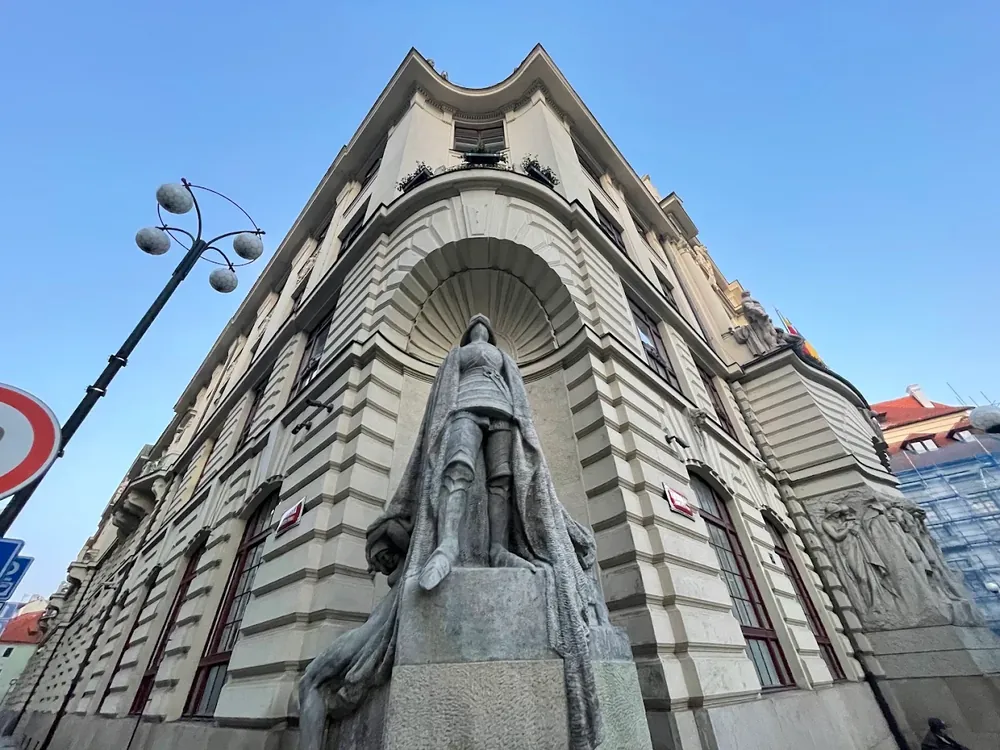 Estatua del Caballero de Hierro en la esquina de un edificio clásico, bajo un cielo azul despejado.