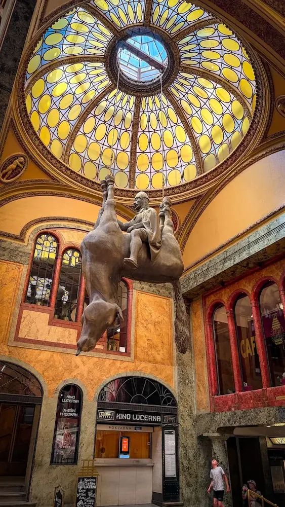 Estatua colgante de un caballero sobre un caballo boca abajo en un palacio con cúpula de vitral.
