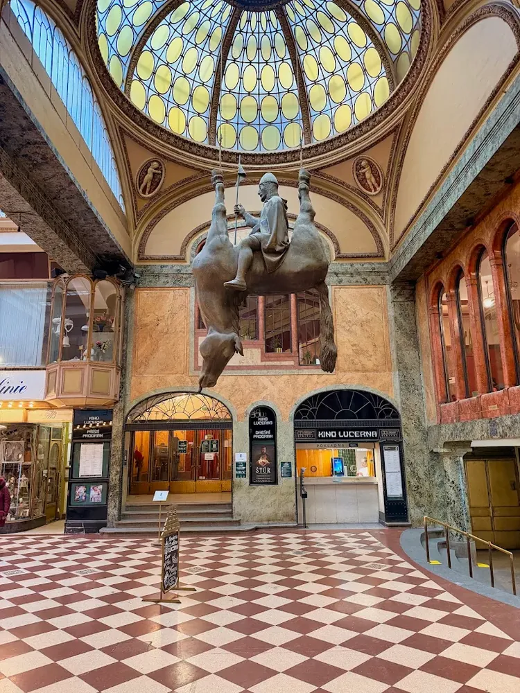 Estatua de un caballero montado en un caballo colgado boca abajo en un vestíbulo con cúpula de cristal.