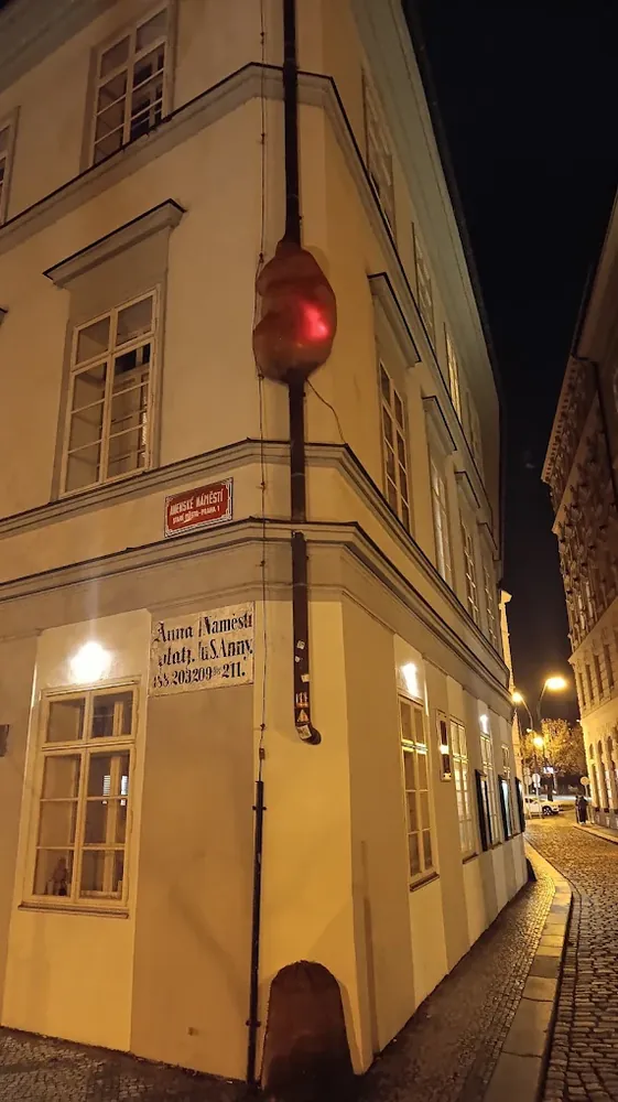 Escultura "Embrión" iluminada en una tubería de una esquina en Praga, de noche.