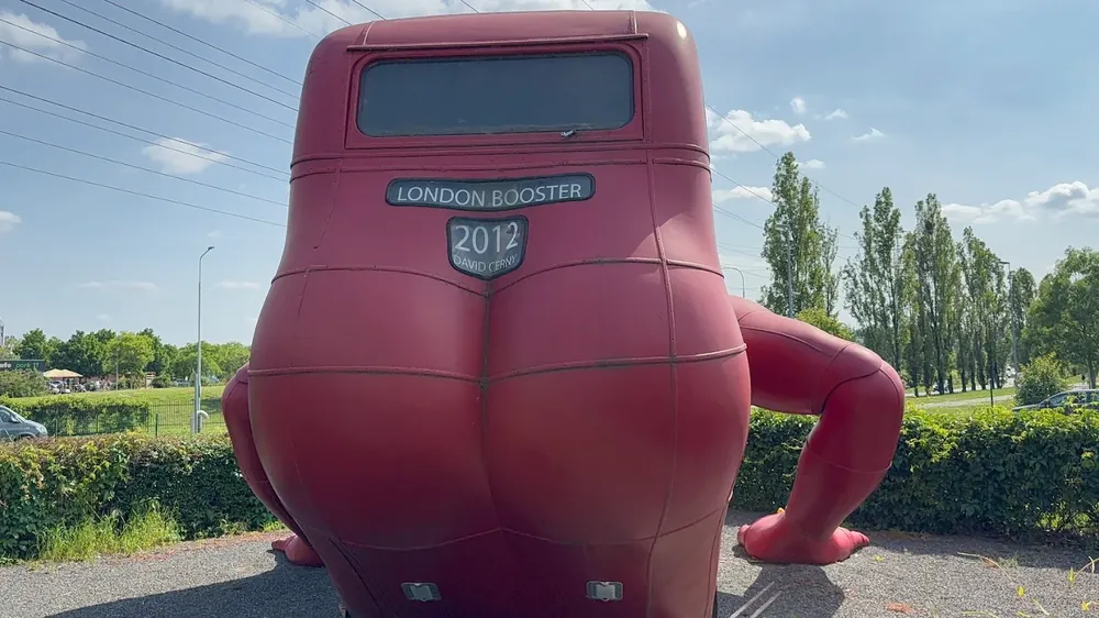 Escultura roja con forma de autobús y glúteos llamada "London Booster" al aire libre.
