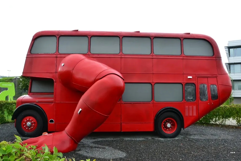 Autobús rojo de dos pisos con una gran pierna articulada del mismo color saliendo de su lateral.
