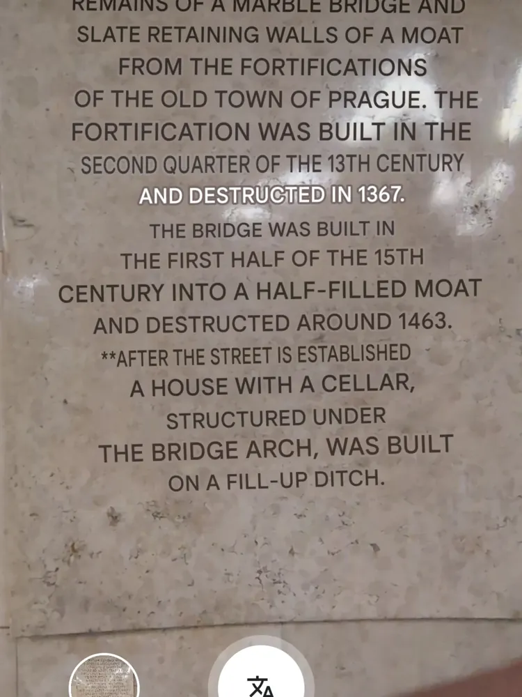 Placa informativa en inglés sobre la historia del Puente Můstek en Praga.