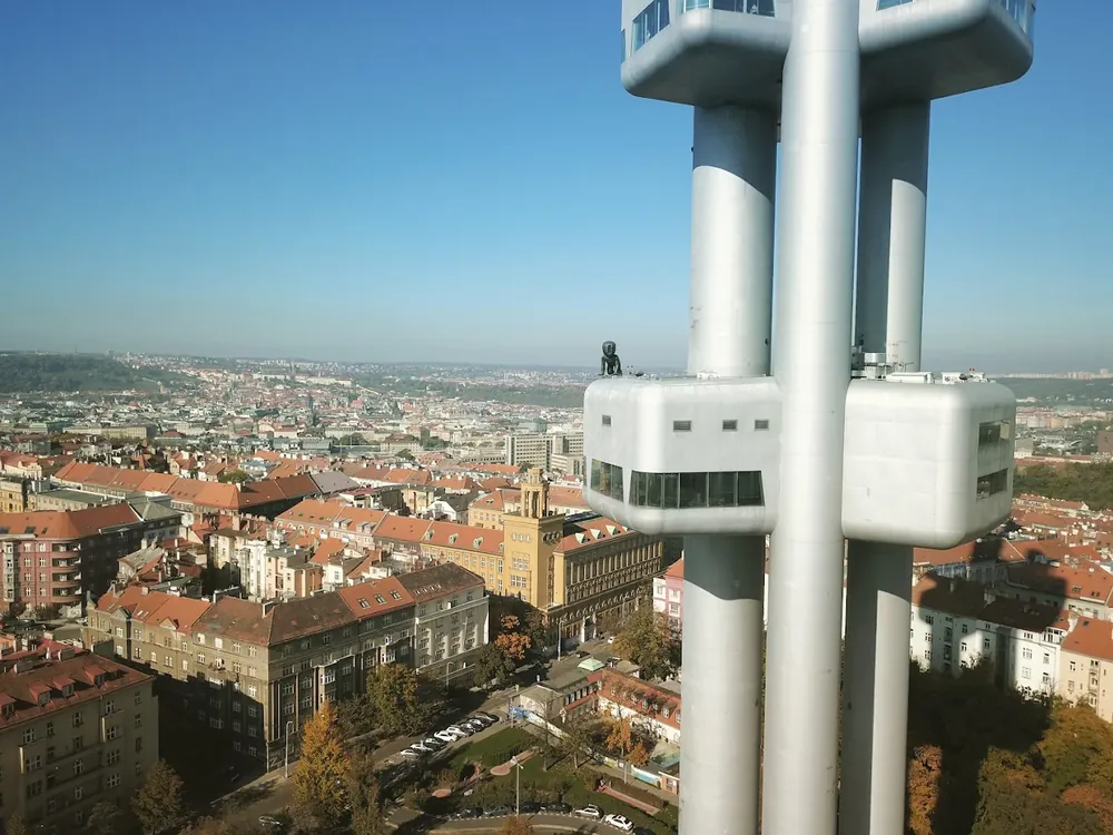 Vista aérea de los pilares metálicos y miradores de la Torre Žižkov frente a un extenso paisaje urbano.